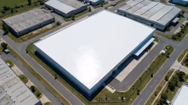 Toiture d'entrepôt industriel traitée par un revêtement réfléchissant blanc, vue aérienne